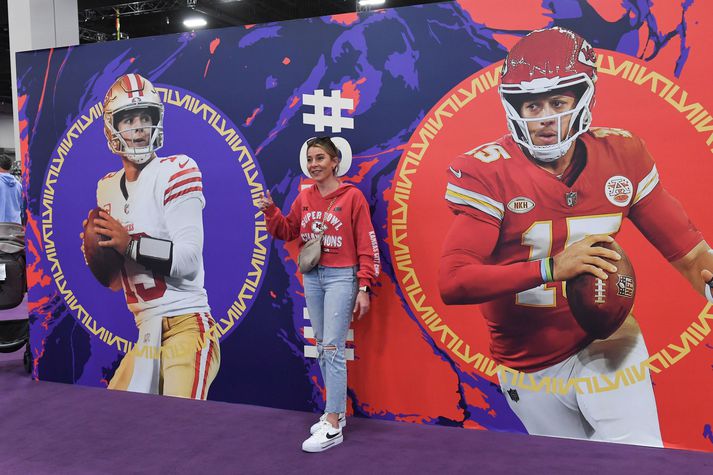 NFL áhugakona stillir sér upp á milli mynda af leikstjórnendunum, Patrick Mahomes og Brock Purdy.