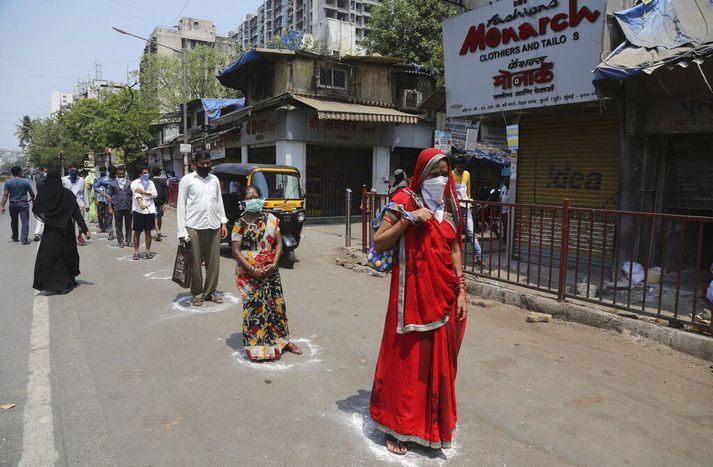 Indverjar standa á merktum stöðum í röð eftir að kaupa nauðsynjar í matvöruverslun í Mumbai. Þriggja vikna útgöngubann tók gildi á miðnætti.