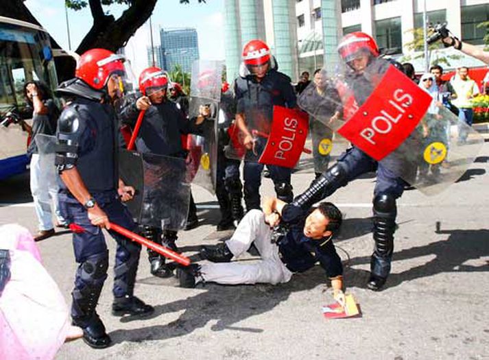 Malasískir lögreglumenn þjarma að mótmælanda í Kuala Lumpur.