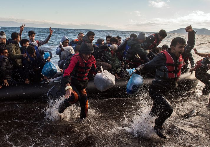 Flóttafólk fagnar við komuna til grísku eyjunnar Lesbos.