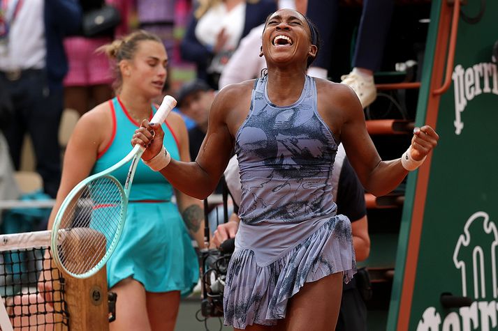 Coco Gauff fagnar hér sigri á Opna franska meistaramótinu en bak við hana má sjá Aryna Sabalenka svekkta eftir tapið.