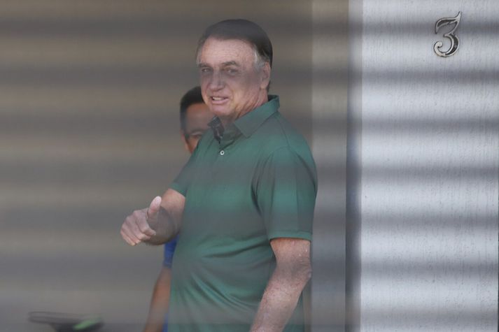 Jair Bolsonaro, fyrrverandi forseti Brasilíu, heilsaði ljósmyndurum fyrir utan heimili hans, þar sem hann er í stofufangelsi.