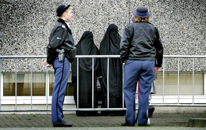 Heittrúaðar í Hollandi. Hollenskar lögreglukonur hafa hér gætur á tveimur konum klæddum að sið strangtrúaðra múslima fyrir utan dómhús í Amsterdam. Þar hófst í gær réttarhald yfir fjórtán mönnum, þar á meðal morðingja hollenska kvikmyndagerðarmannsins Theo van Gogh, en þeir eru ákærðir fyrir aðild að leynifélagi herskárra múslima og að leggja á ráðin um að sýna hollenskum stjórnmálamönnum banatilræði.