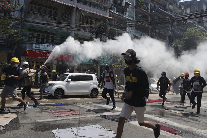 FILE - In this March 8, 2021, file photo, an anti-coup protester discharges a fire extinguisher to counter the impact of the tear gas fired by police during a demonstration in Yangon, Myanmar. The plentiful and unsettling imagery from protests, filmed by participants on the ground and uploaded, is bringing protests and crackdowns to millions of handheld devices almost immediately. (AP Photo/File)