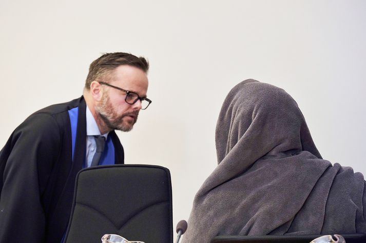 Páll Rúnar Mikael Kristjánsson, verjandi Thomasar, ræðir við skjólstæðing sinn sem hylur andlit sitt þegar ljósmyndarar eru nærri.