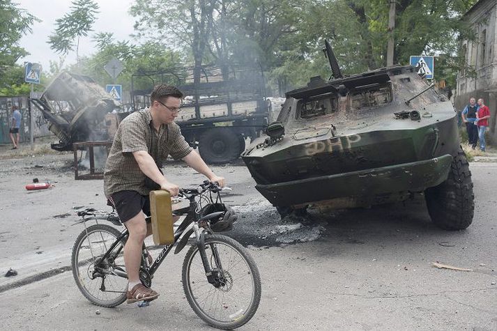 Íbúi Mariupol hjólar fram hjá skriðdreka eftir átökin í gær.
