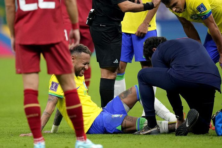 Neymar situr sárþjáður á grasinu eftir að hafa meiðst á hægri ökkla í sigurleik Brasilíu í gær.