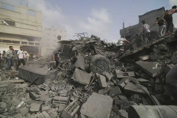Palestínumenn leita aðstandenda í rústum byggingar sem varð fyrir sprengjuregni Ísraelshers í dag. 