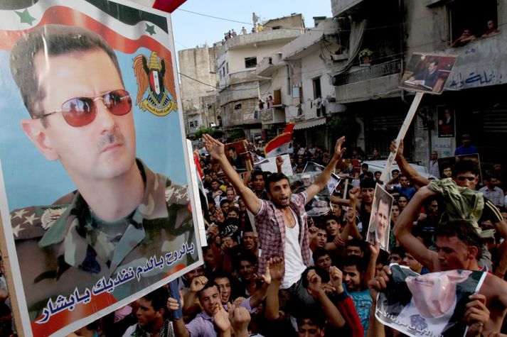 Hér safnast mótmælendur saman undir mynd af forseta Sýrlands, Bashar al-Assad.