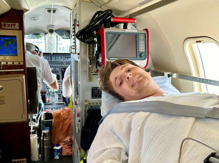 Elliot í sjúkraflugi frá Íslandi heim til Norwich. Þar tók við tveggja vikna spítalavist til viðbótar við þriggja vikna dvöl á Landspítalanum.